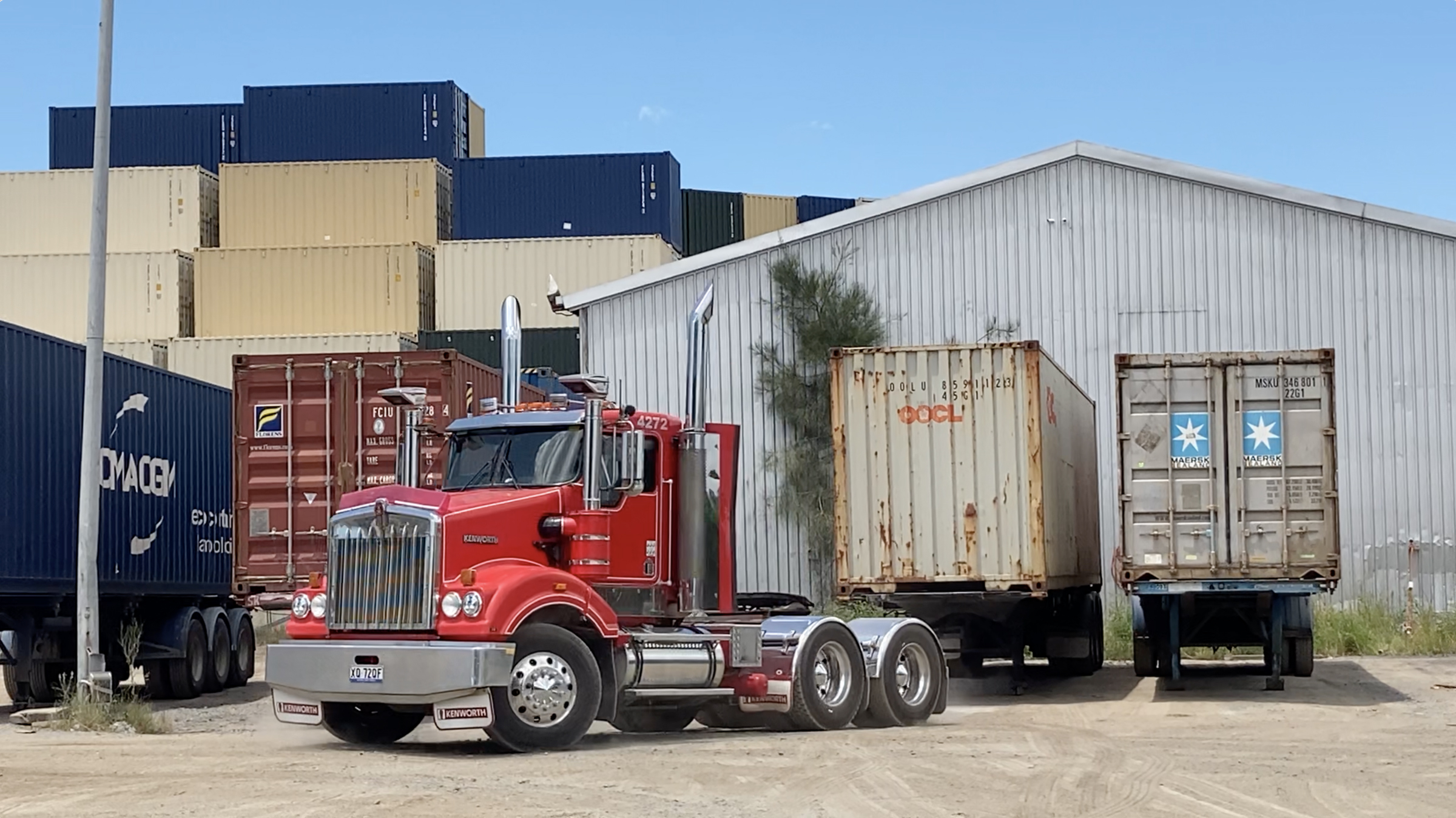 Red Kenworth truck driving away after offloading container