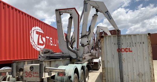A machine with long arms lifting a shipping container